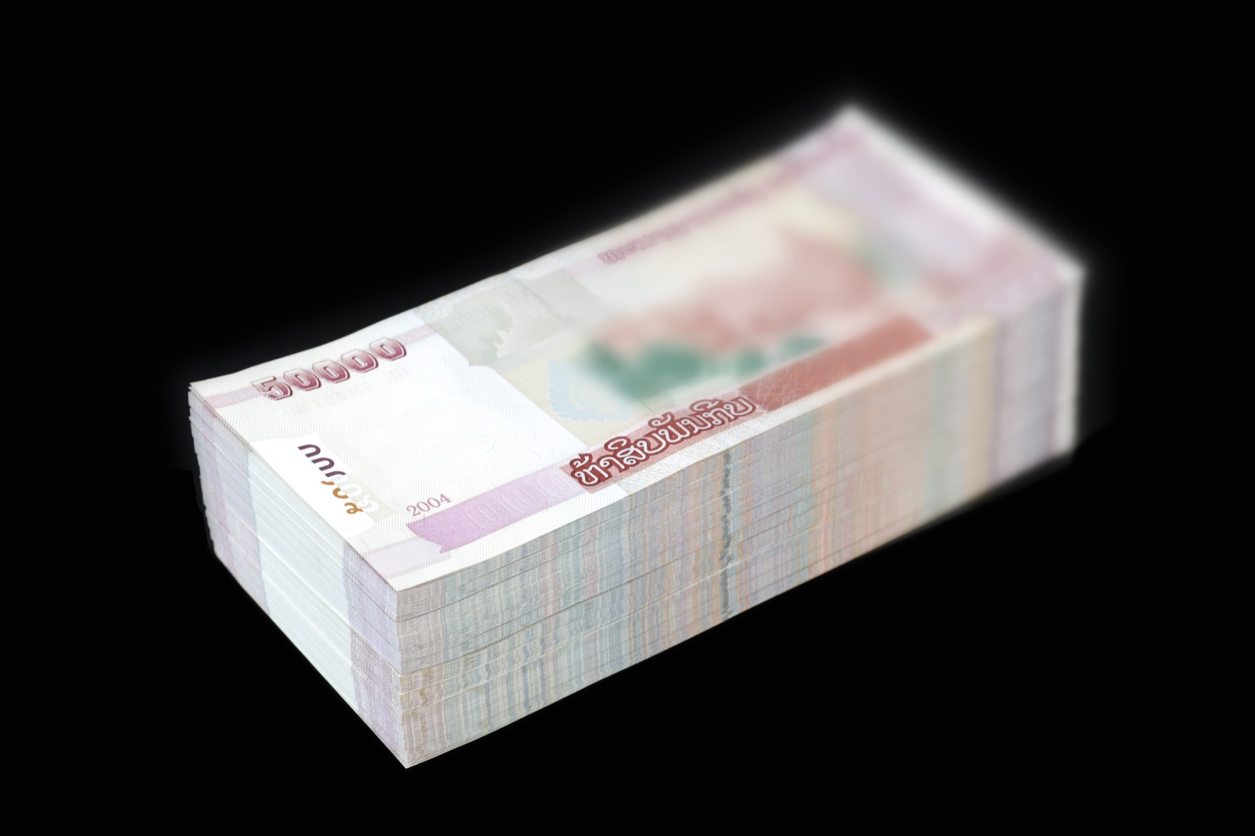 A thick stack of Lao kip banknotes, the everyday currency a foreign buyer's money converts into on the ground