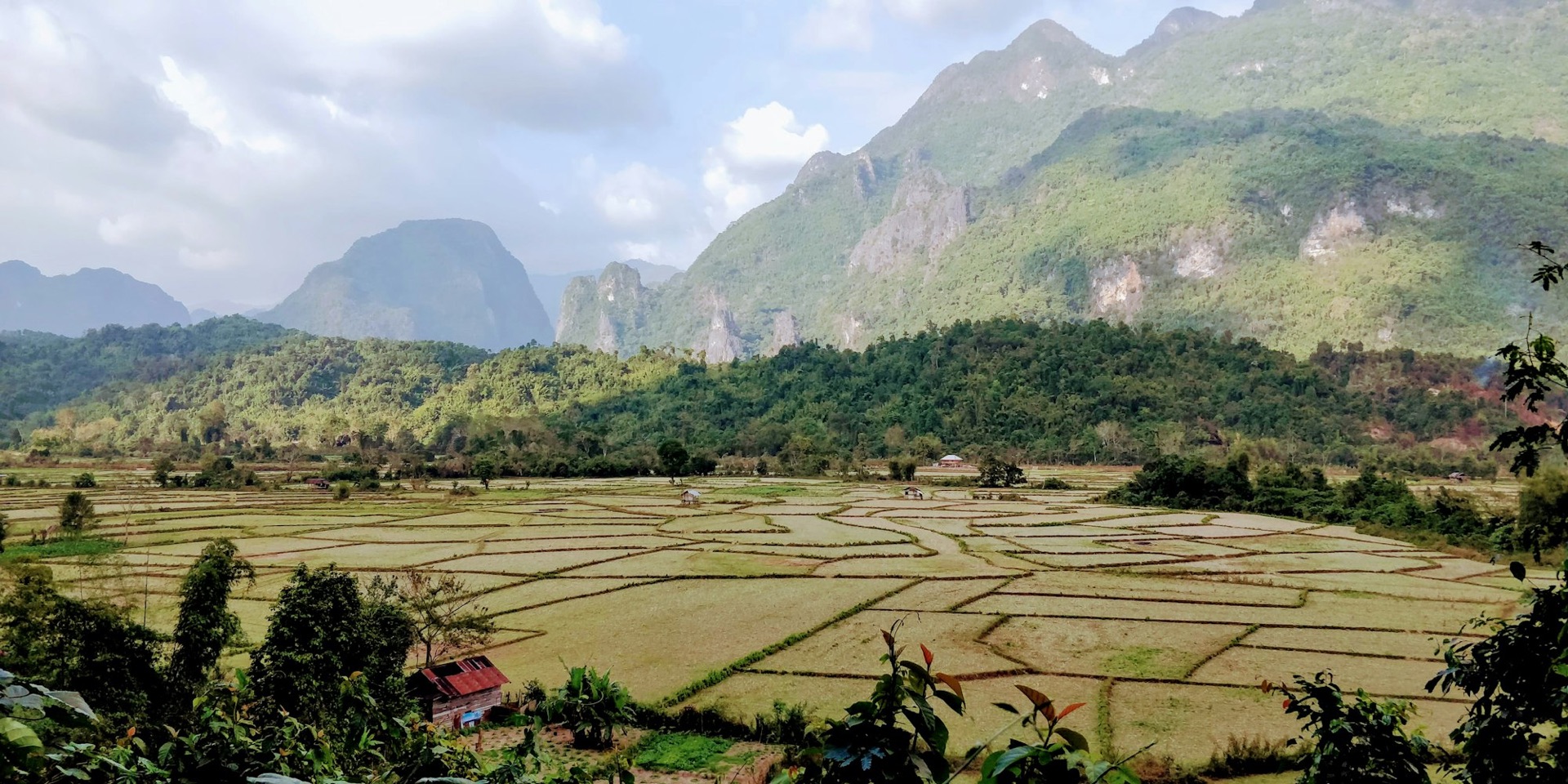 Lao farmland divided into registered parcels beneath limestone karst, the land a title describes