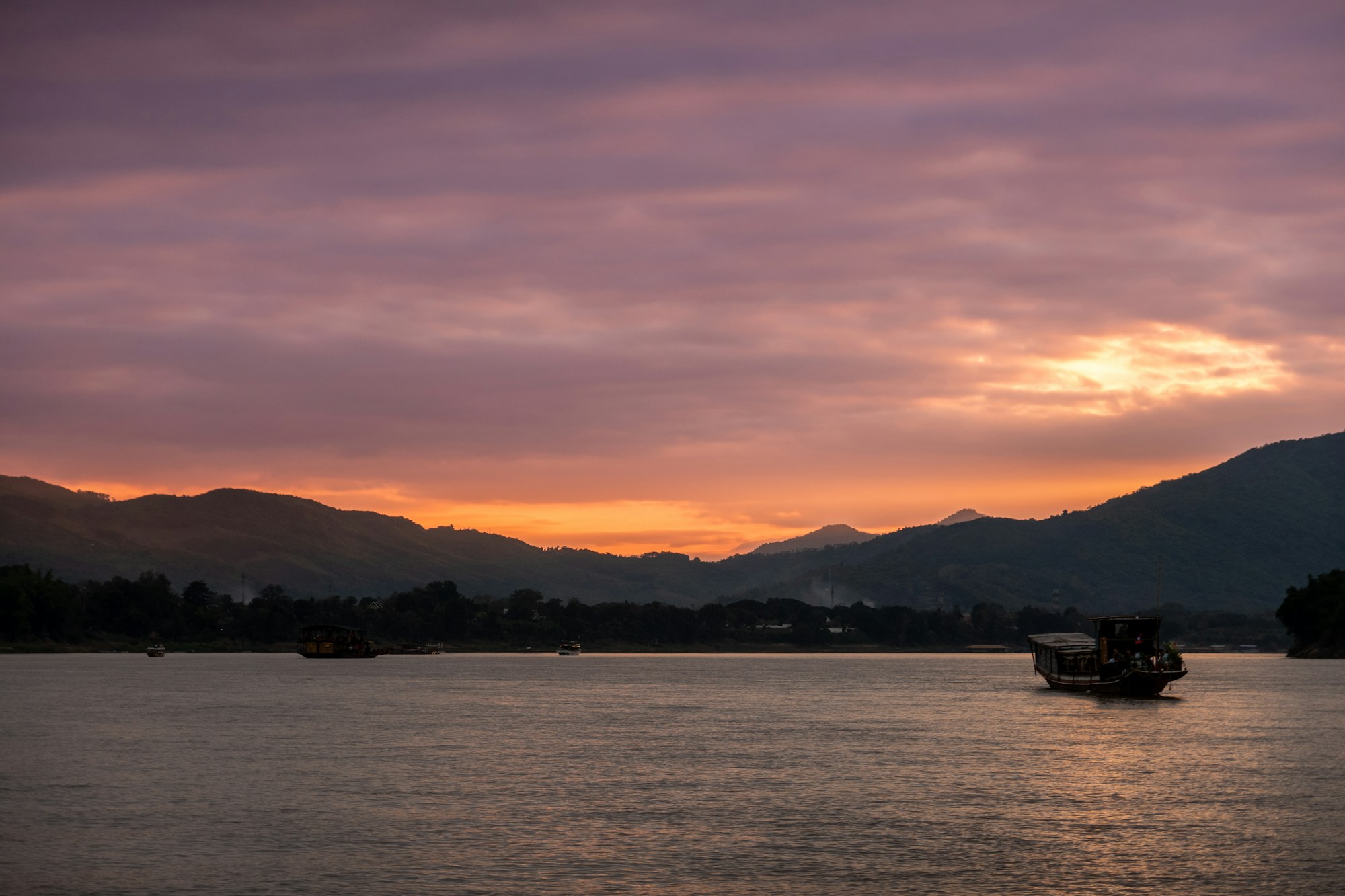 Une barque solitaire sur le Mékong paisible au crépuscule, au Laos