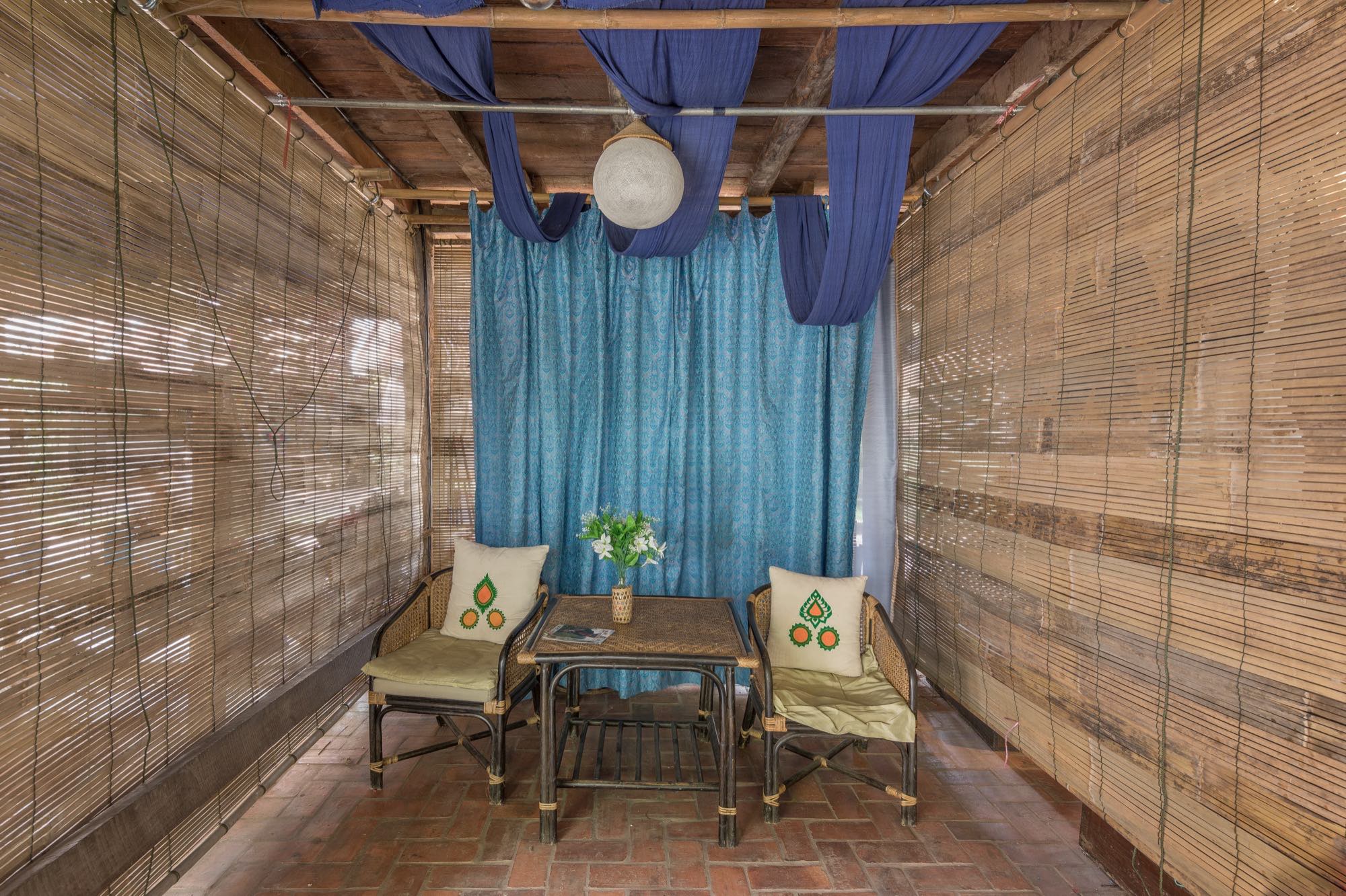 Intérieur chaleureux d'une maison patrimoniale lao restaurée à Luang Prabang, mobilier de bambou et lumière douce, l'image d'un foyer bâti à deux