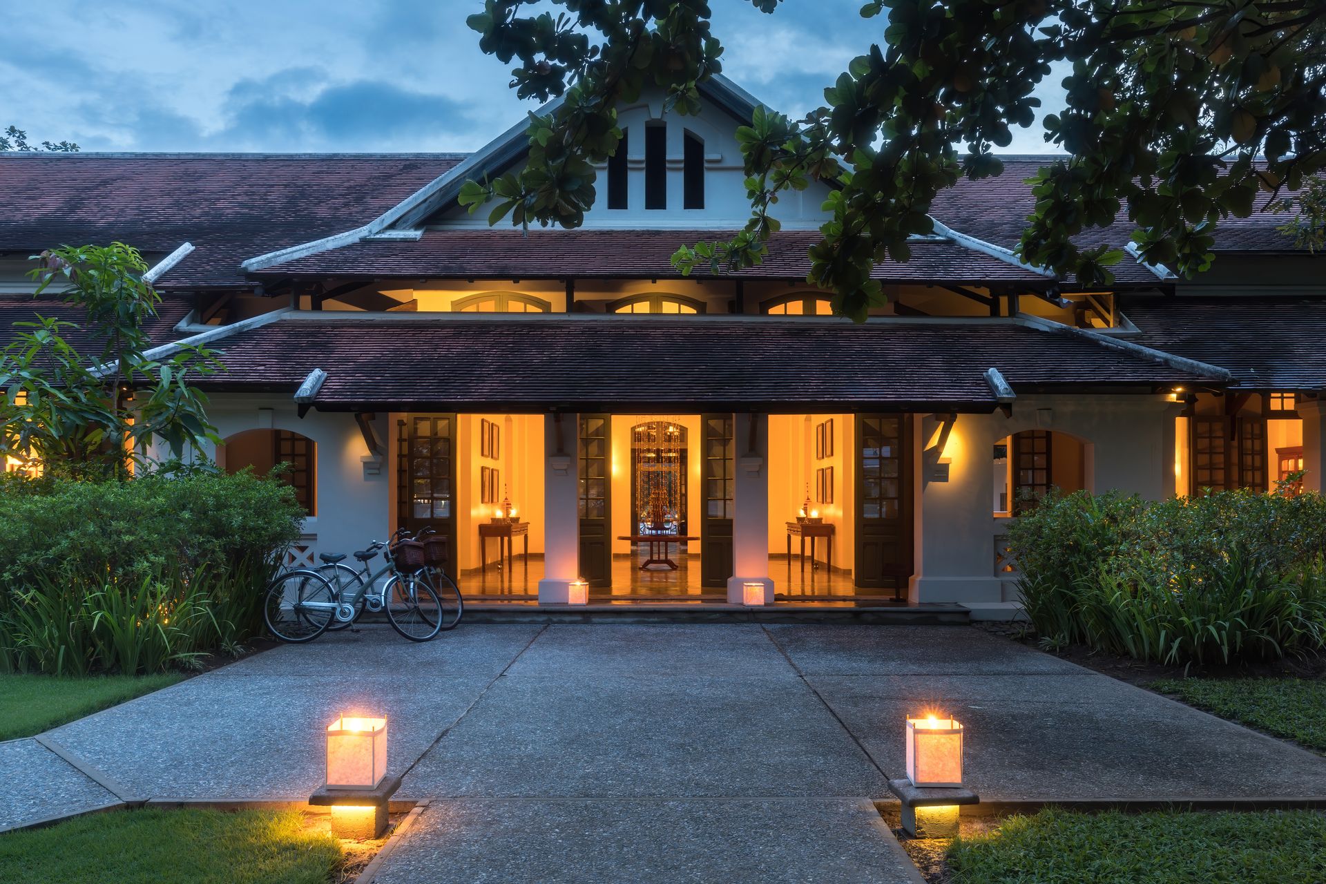 Một biệt thự kiểu thuộc địa ở Luang Prabang vào giờ xanh, ánh đèn ấm hắt ra từ bên trong
